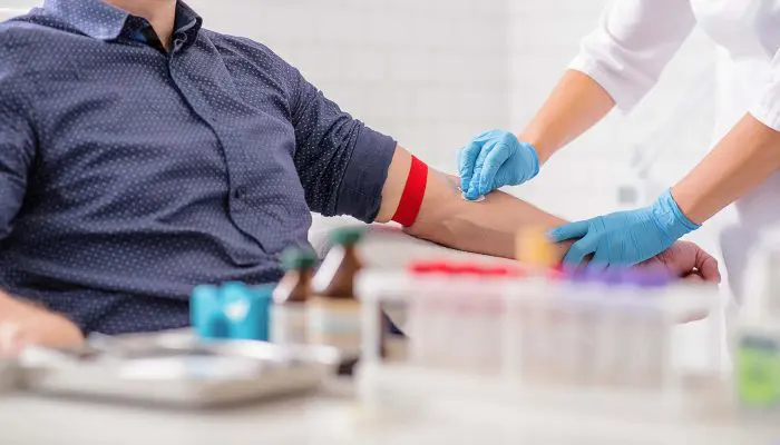 Close up of nurse disinfecting male arm before blood test. Man is sitting on chair near medical set